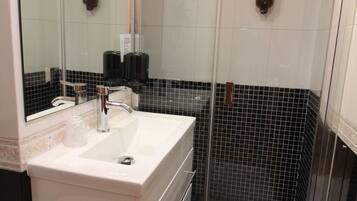 A modern bathroom with a white sink, a glass shower enclosure, and a mirror.