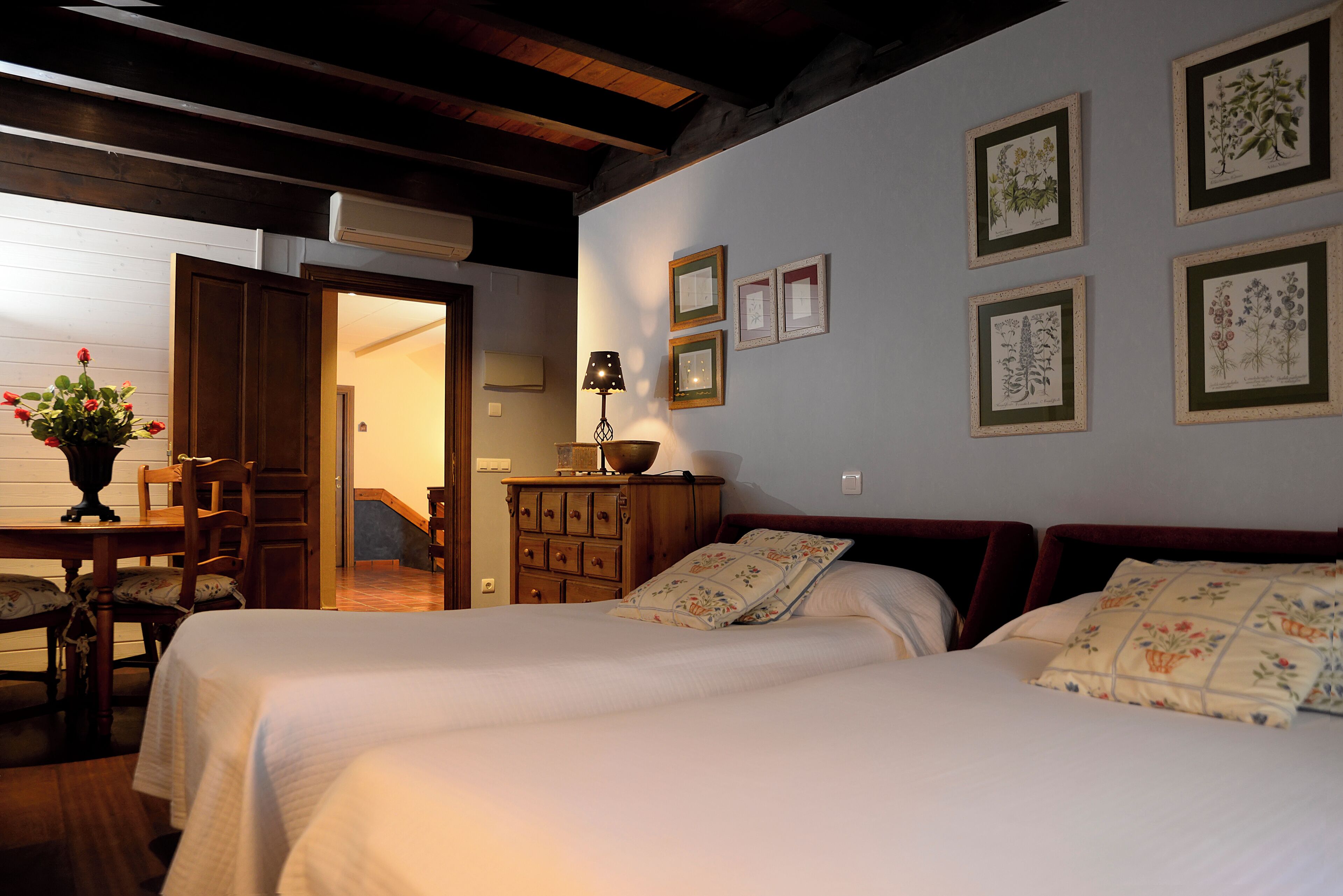 Una camera da letto con due letti, una cassettiera in legno, una scrivania con sedia e una lampada.