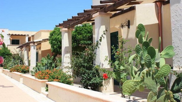 A row of buildings with a pergola structure, outdoor plants, and a clear blue sky. - L'Arco del Saracino (Salve)