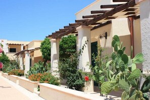 A row of buildings with a pergola structure, outdoor plants, and a clear blue sky. - L'Arco del Saracino (Salve)