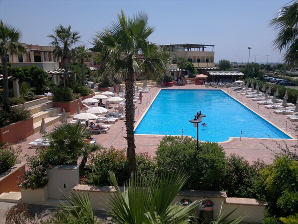 Una piscina al aire libre, sombrillas, tumbonas