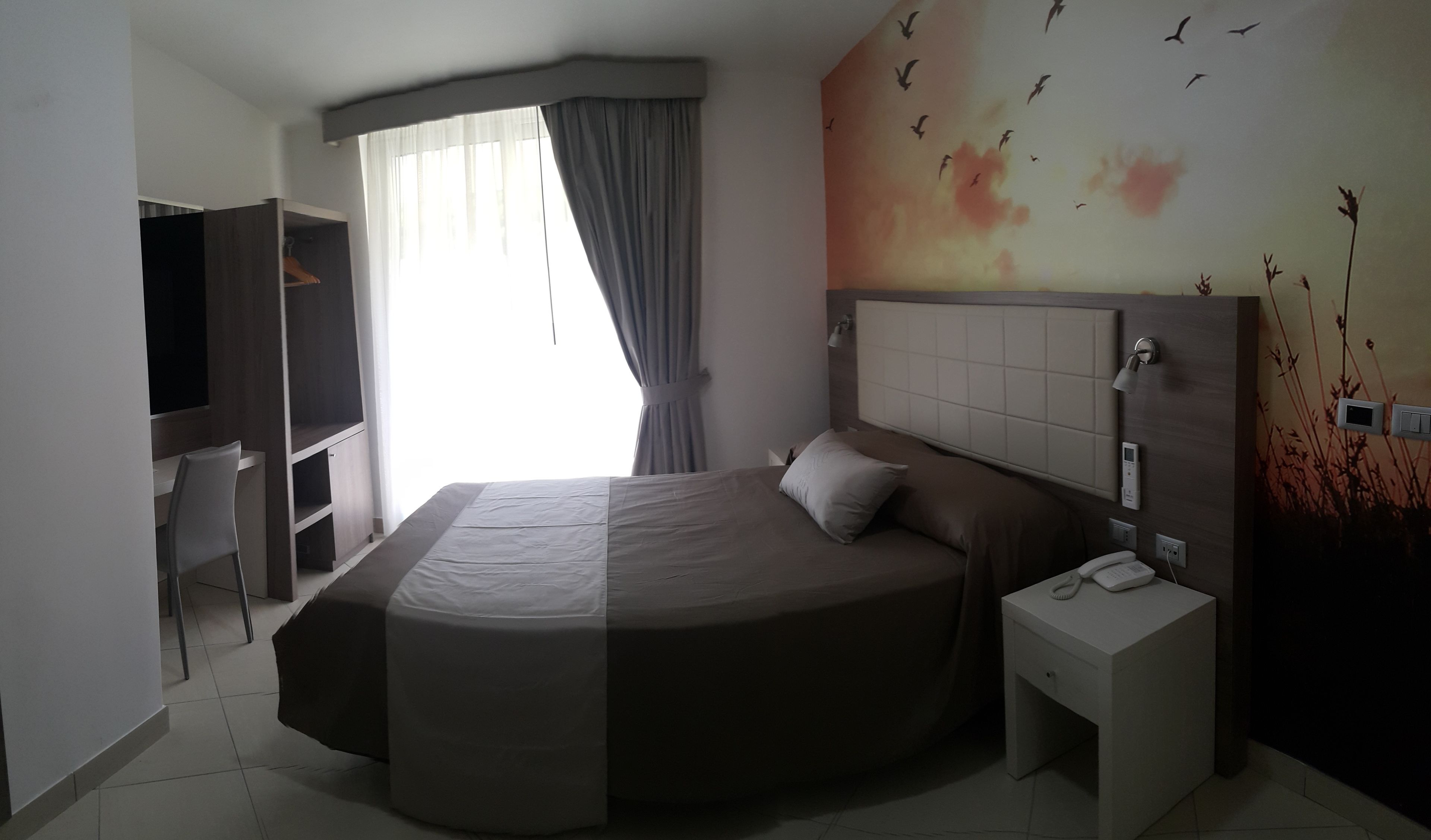 Une chambre d’hôtel moderne, dotée d’un grand lit, d’un bureau et d’une télévision.