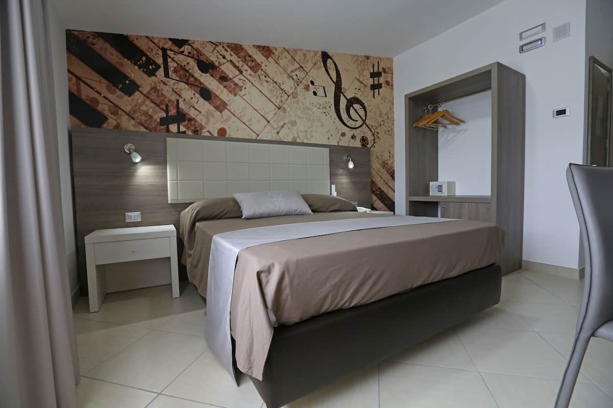 A modern bedroom with a large bed, bedside tables, a wardrobe, and a mirror.