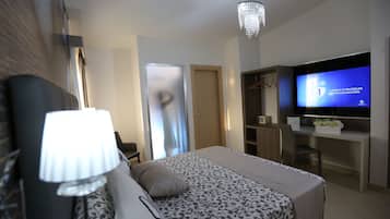 Ett modernt hotellrum med en säng, ett skrivbord, en tv och en kristallkrona.