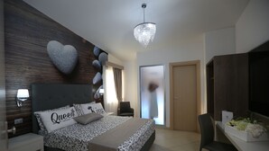 A modern bedroom with a large bed, a chandelier, a desk, and a TV. - Medea Resort (Bellona)