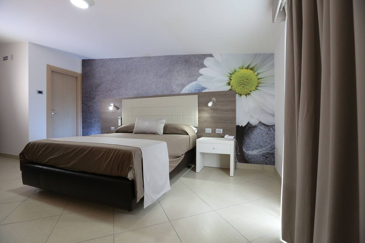 A modern bedroom with a bed, bedside tables, and a wall mural.