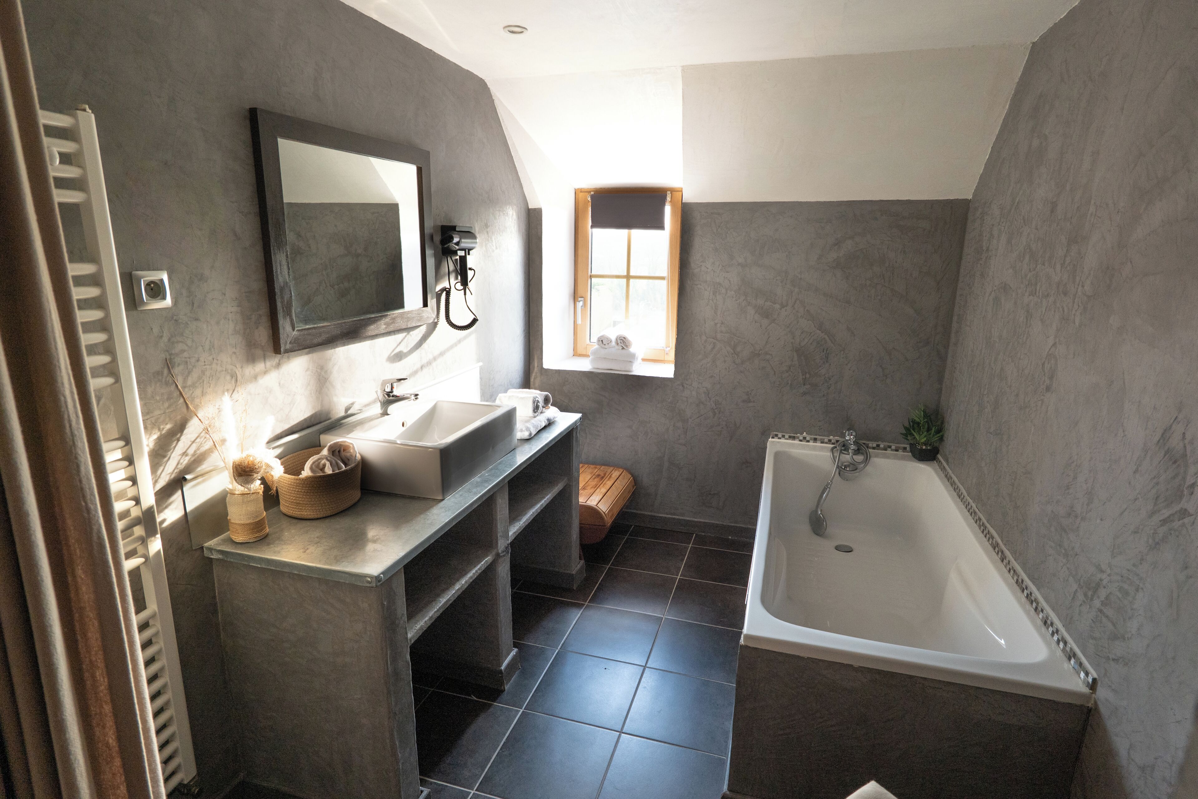 Une salle de bain avec une baignoire, un lavabo, un miroir et une fenêtre.