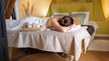 A spa room with a massage table, candles, and a wooden tray.