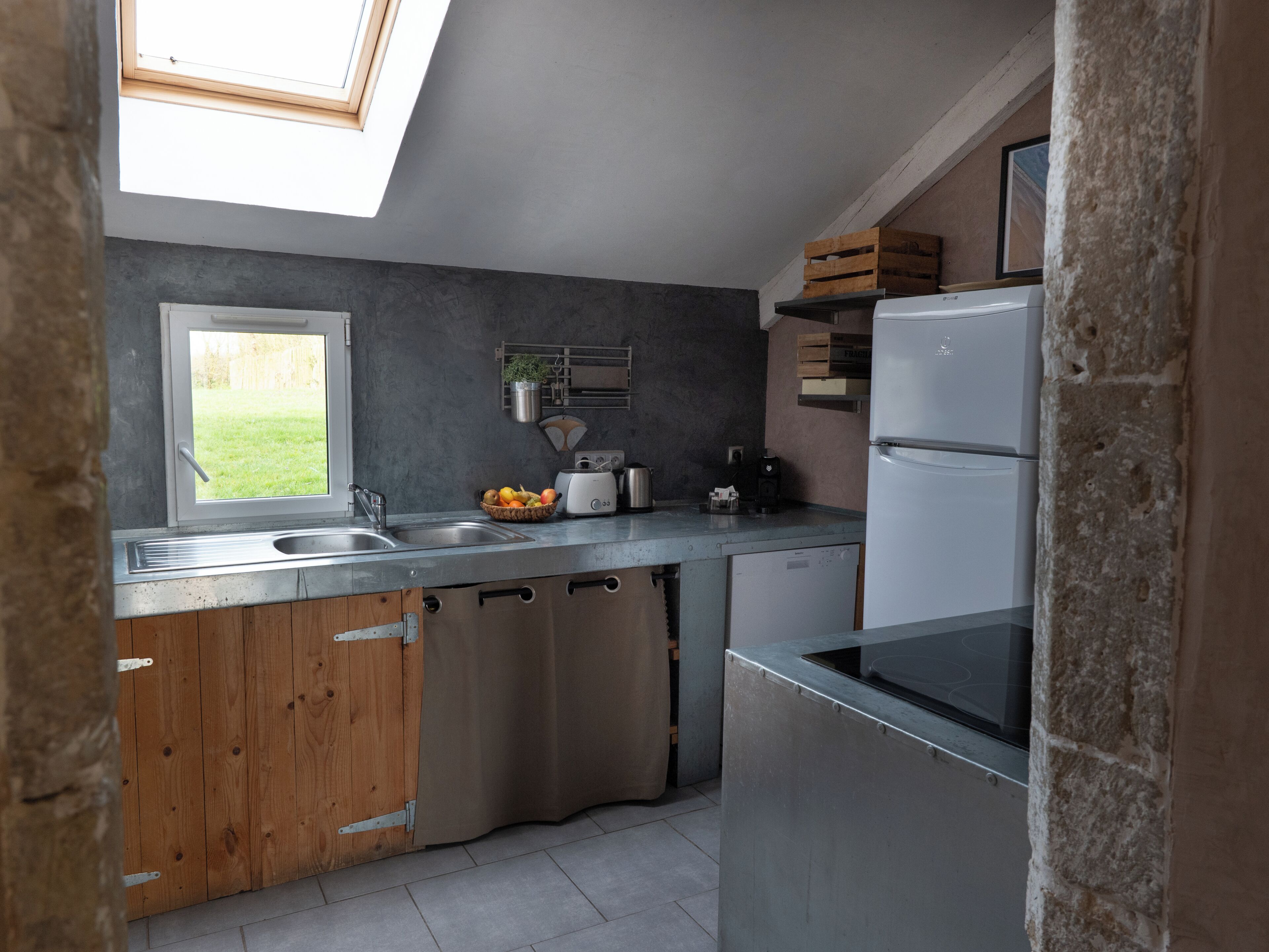 A modern kitchen with a skylight, stainless steel appliances, and wooden cabinets.