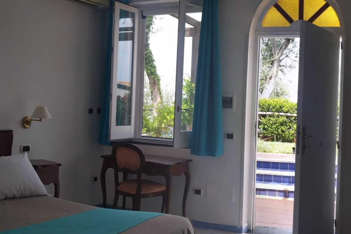 A hotel room with a bed, a desk, and a window with curtains.