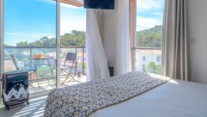 A hotel room with a large bed, a TV mounted on the wall, and a balcony with a table and chairs. - Sure Hotel by Best Western Saint-Raphael Le Dramont (Saint-Raphael)