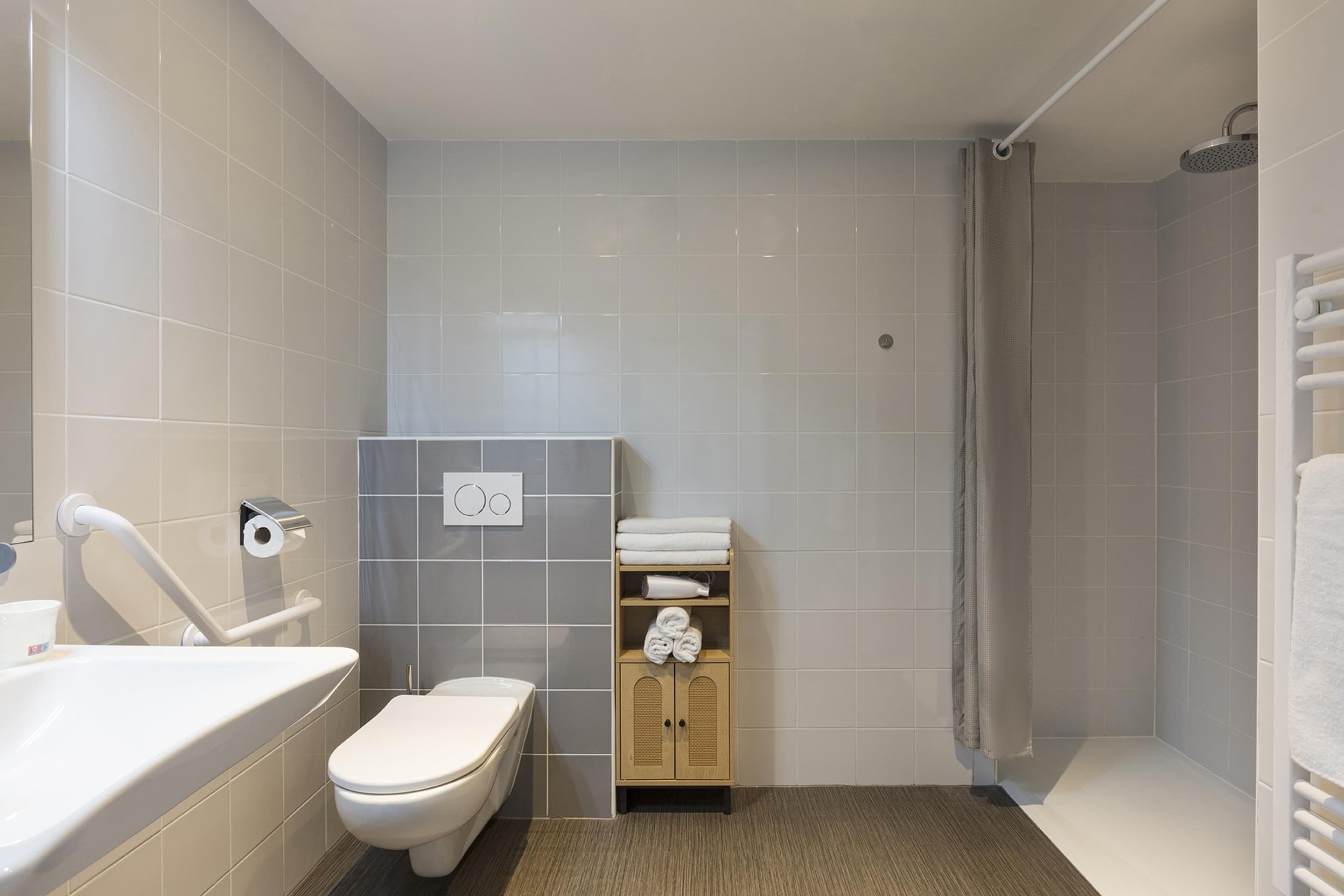 A bathroom with a toilet, a sink, a shower, and a towel rack.