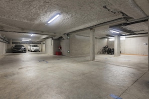 Autotalli, jossa on betonipilarit, loisteputkivalaistus ja merkityt parkkipaikat.