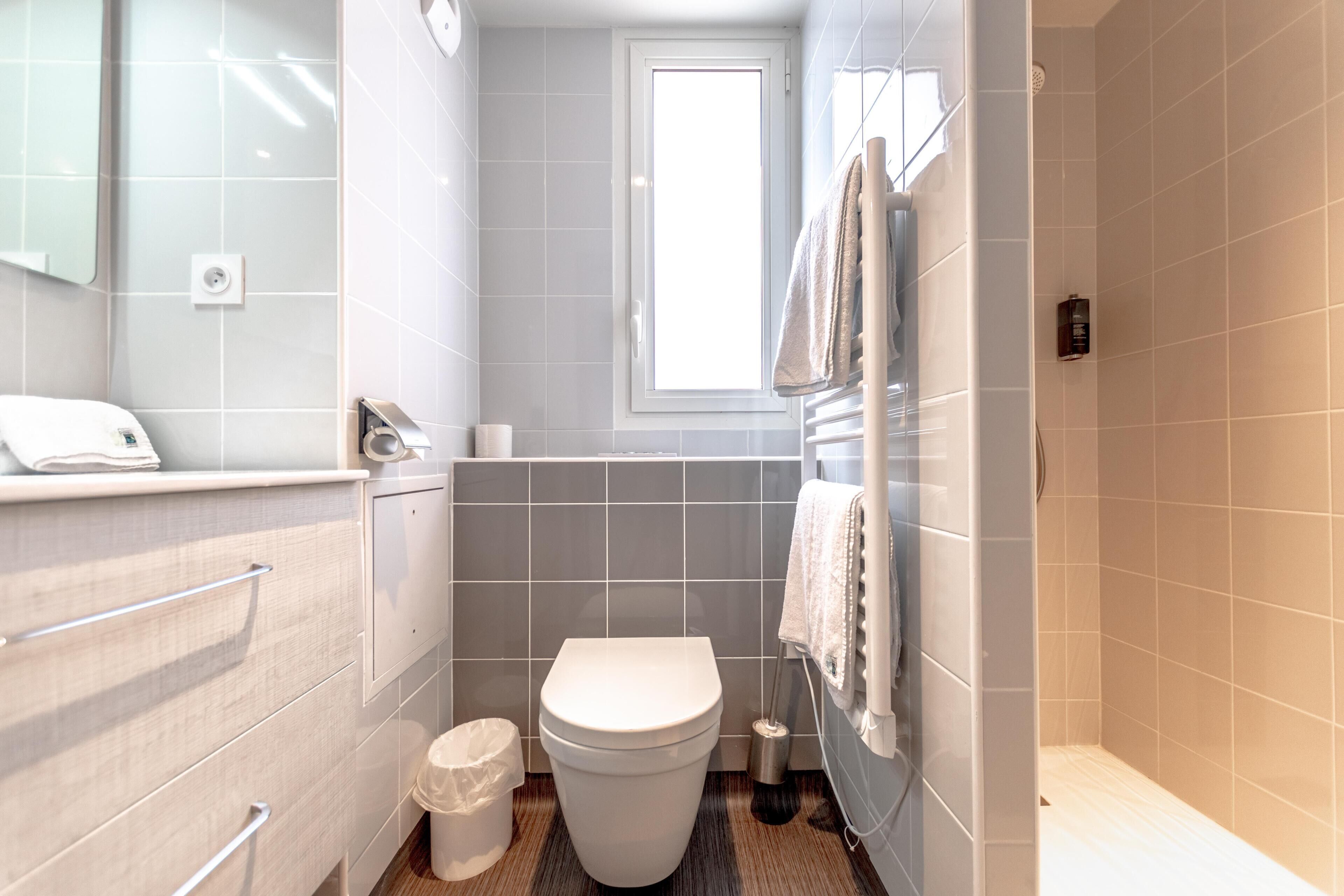 A small, modern bathroom with a toilet, sink, and towel rack.