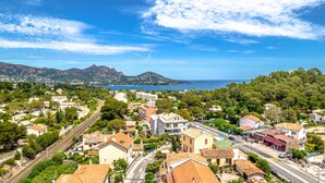A coastal town with a mix of residential and commercial buildings, a railway line, and a view of the sea and mountains in the background. - Sure Hotel by Best Western Saint-Raphael Le Dramont (Saint-Raphael)