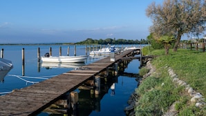 A wooden dock extending into calm water with boats moored at the end. - Capri (Grado)