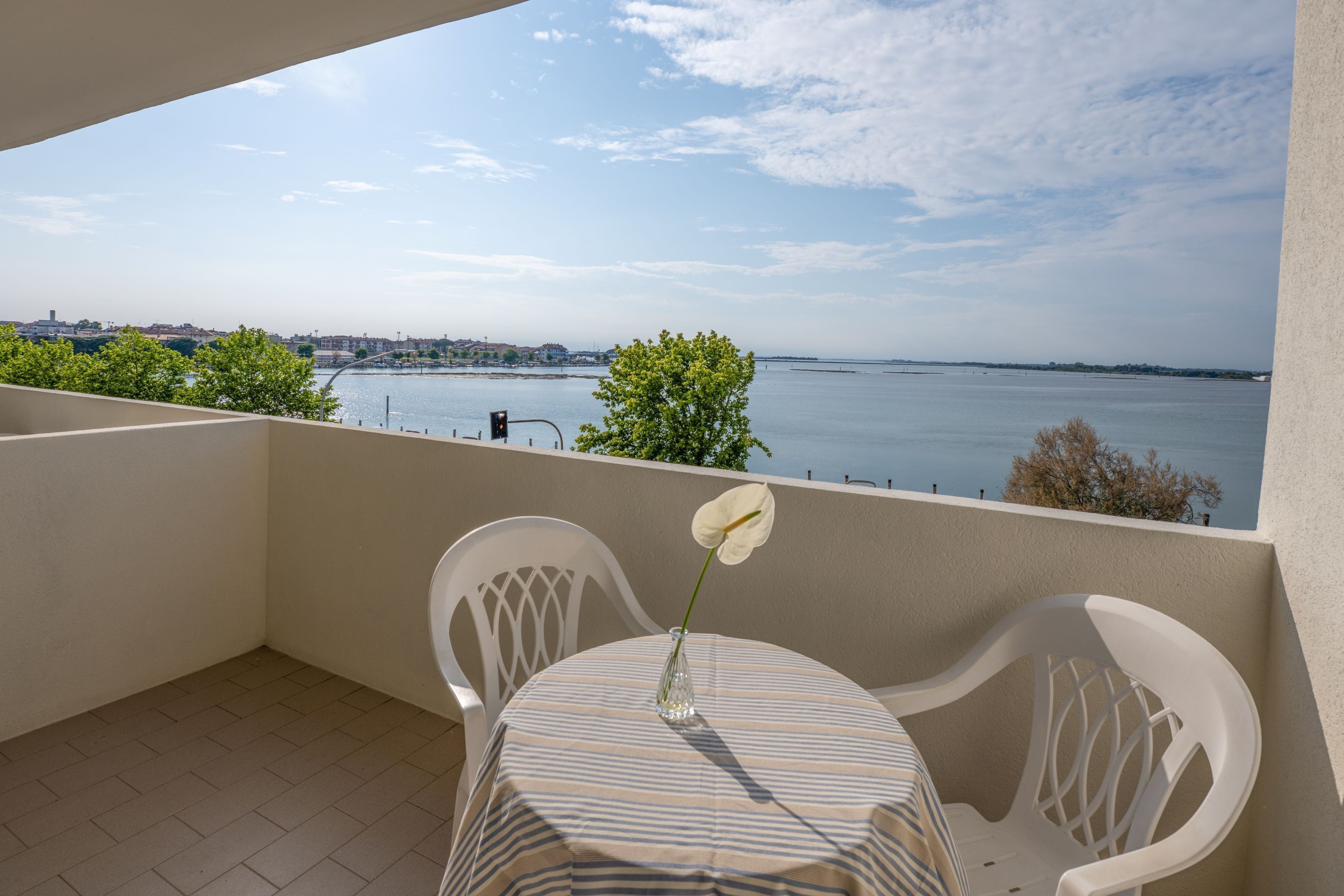 A balcony with a table, chairs, and a vase with a flower.