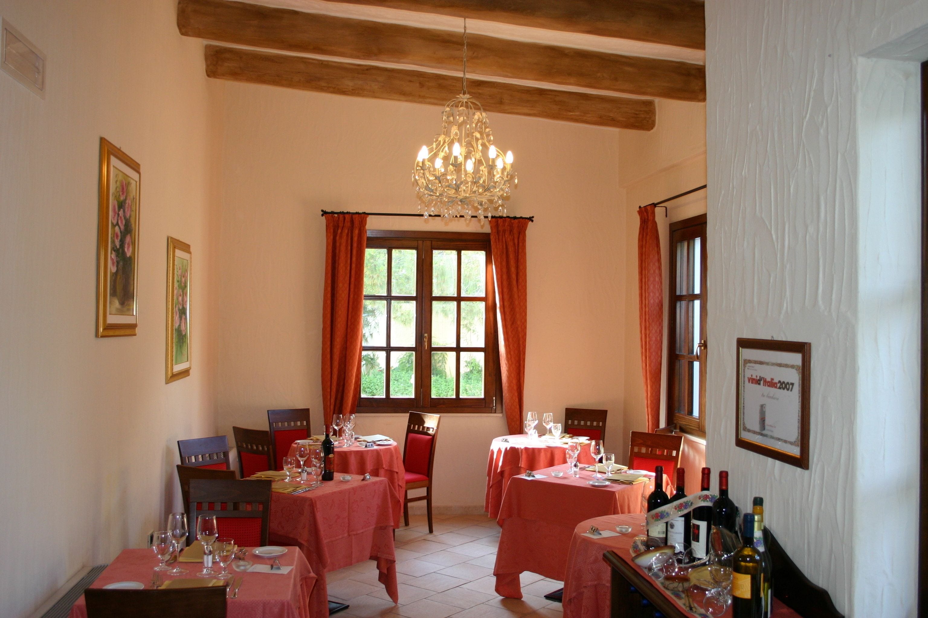 A dining area with tables set for a meal, a chandelier, and framed pictures on the walls.