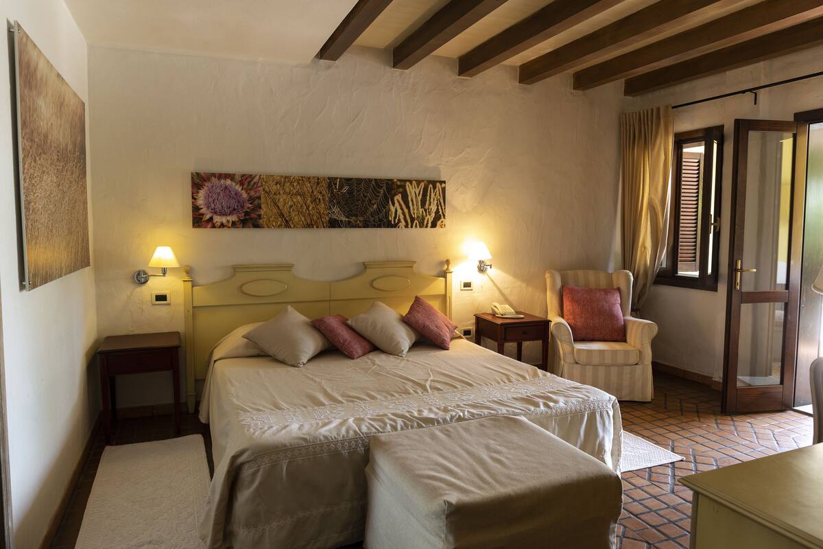 Une chambre à coucher avec un lit, des tables de chevet, une chaise et une porte.