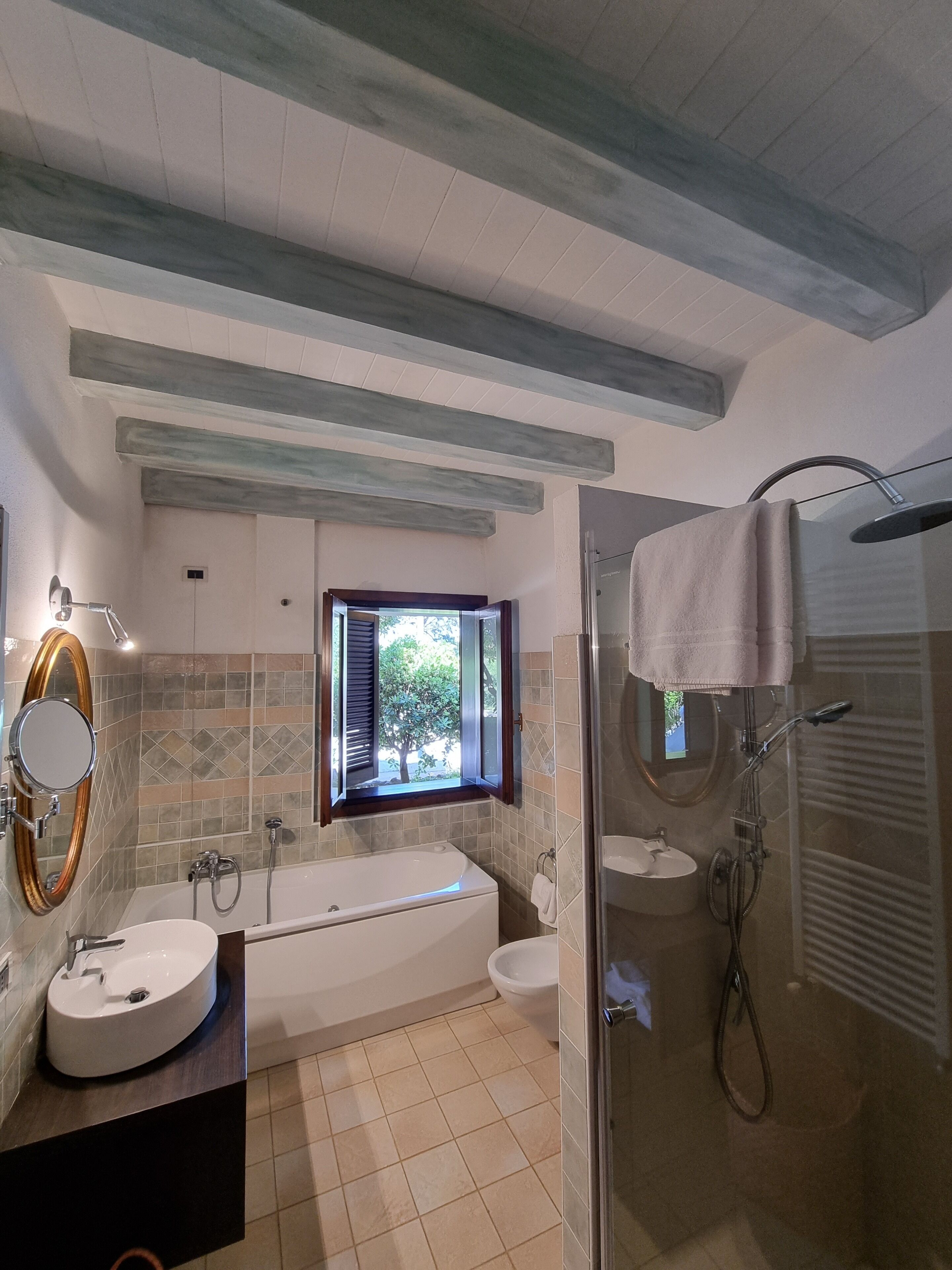 Un baño moderno con bañera, ducha y lavamanos. Hay una ventana que proporciona luz natural y vistas al exterior.