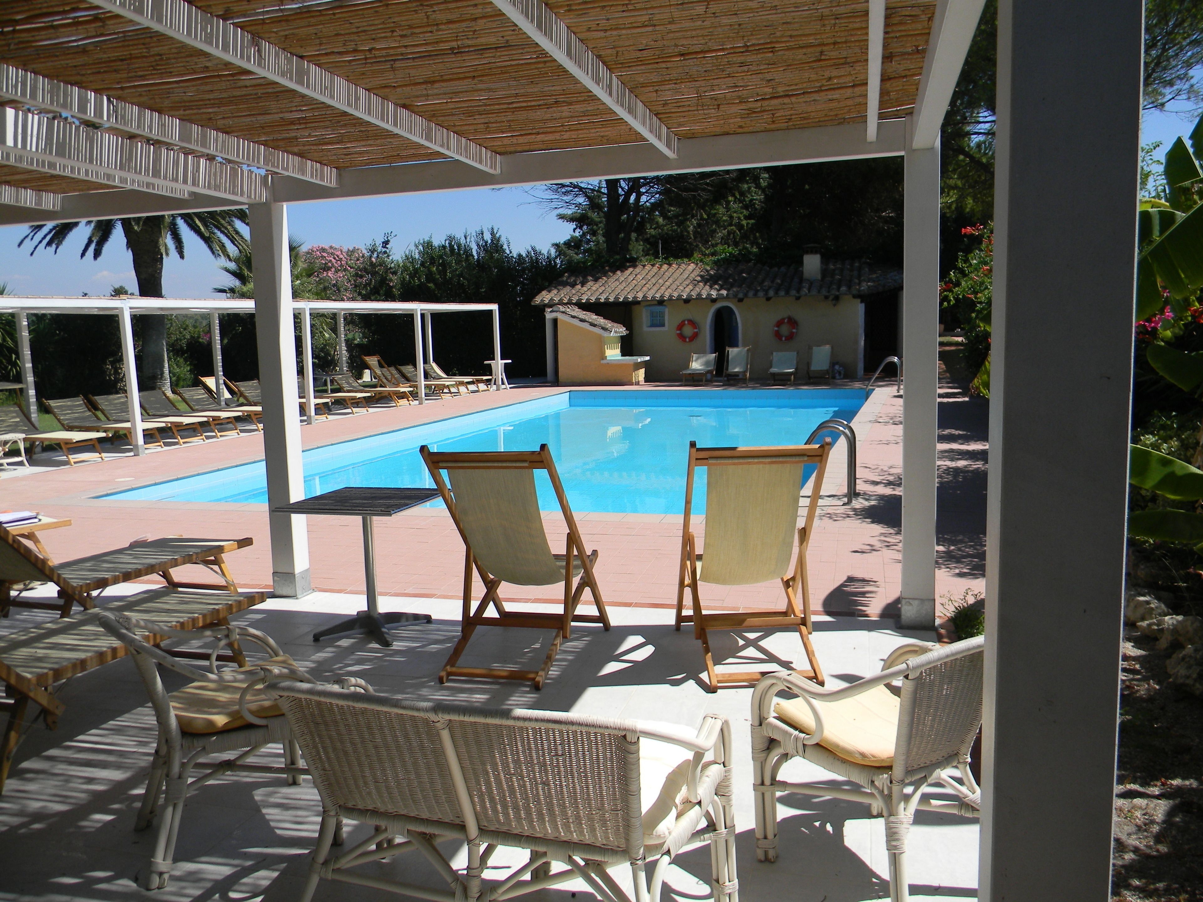Ein überdachter Poolbereich mit Liegestühlen und einem kleinen Tisch.