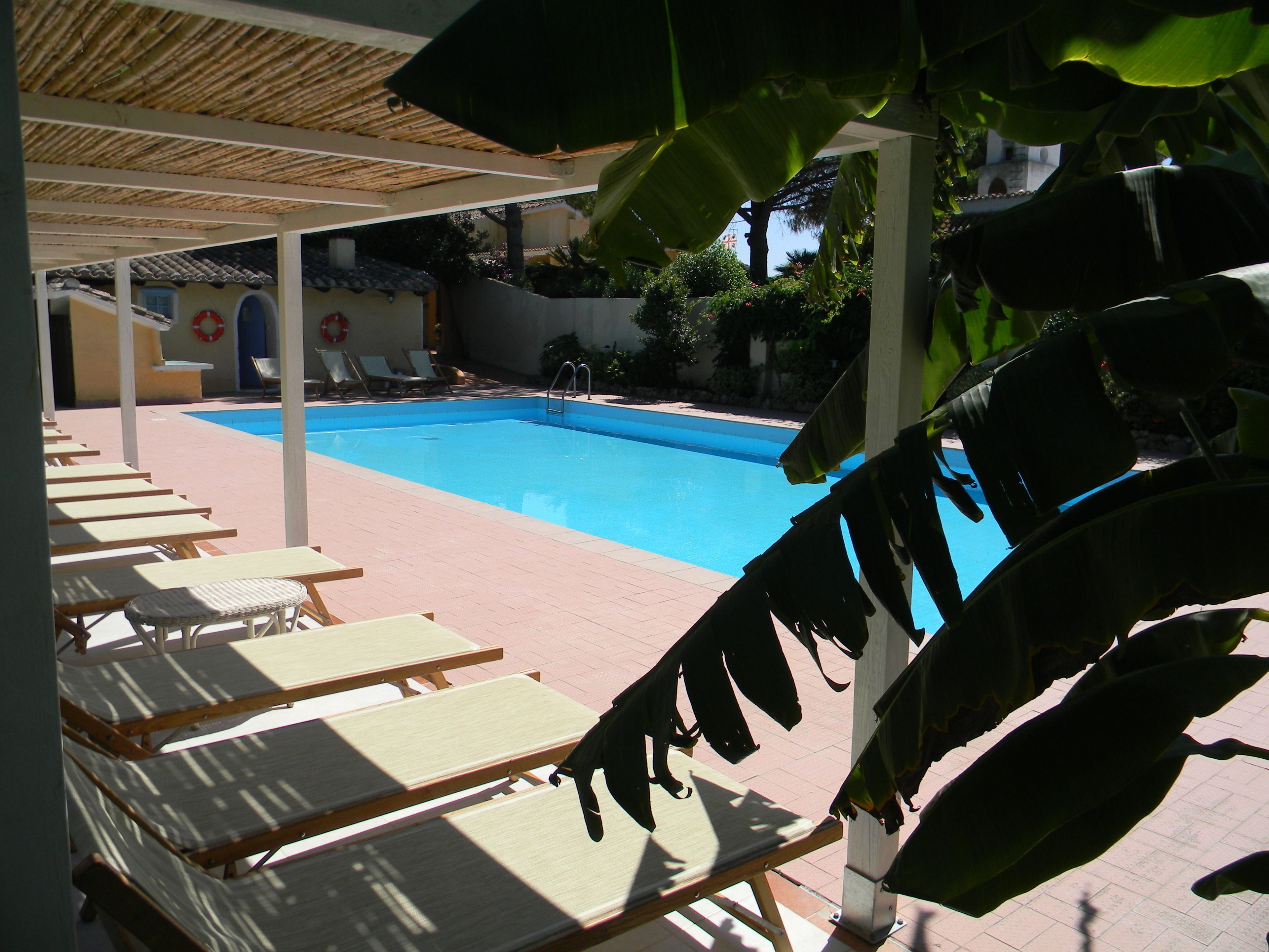 Zona de piscina con sillones de descanso y un flotador en la pared.