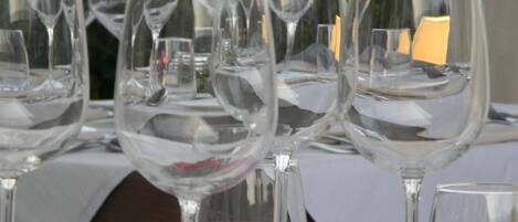 A table set with multiple wine glasses, forks, and spoons, with a candle and flowers on the table.