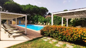 Una piscina con sillas de descanso y una zona de estar cubierta.