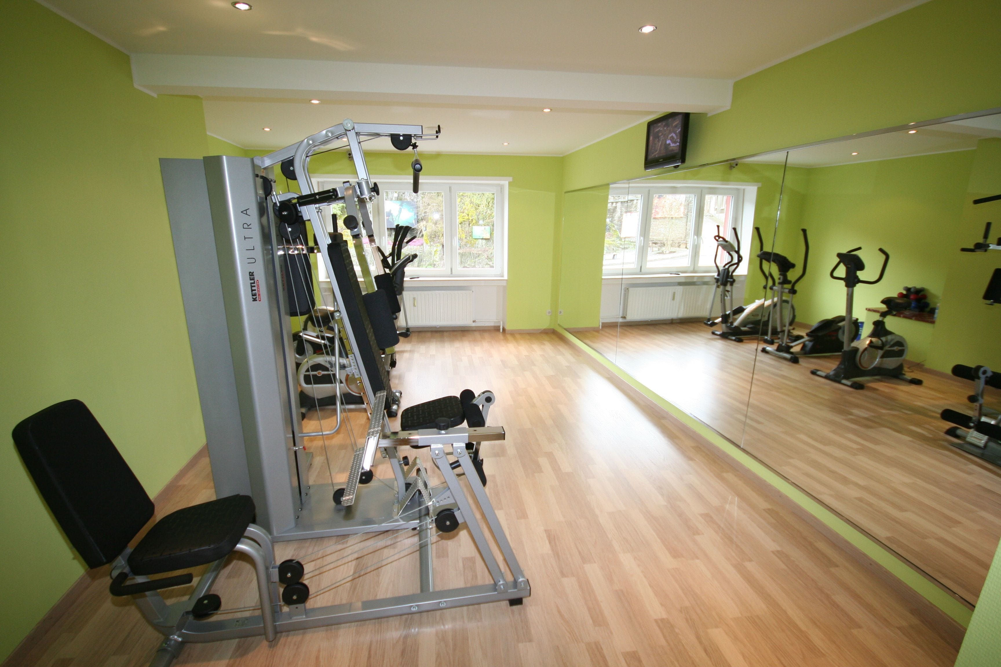 Une salle de sport équipée de matériel d’exercice, d’un miroir et d’une fenêtre.