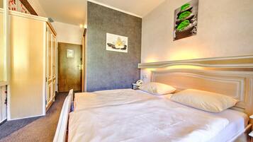 Une chambre d’hôtel avec un grand lit, une armoire, une porte et un mur orné d’un tableau.