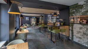 Een moderne bar met hoge krukken, een toonbank en hanglampen.