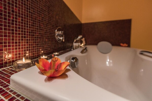 Un baño con bañera, espejo y pared de azulejos.