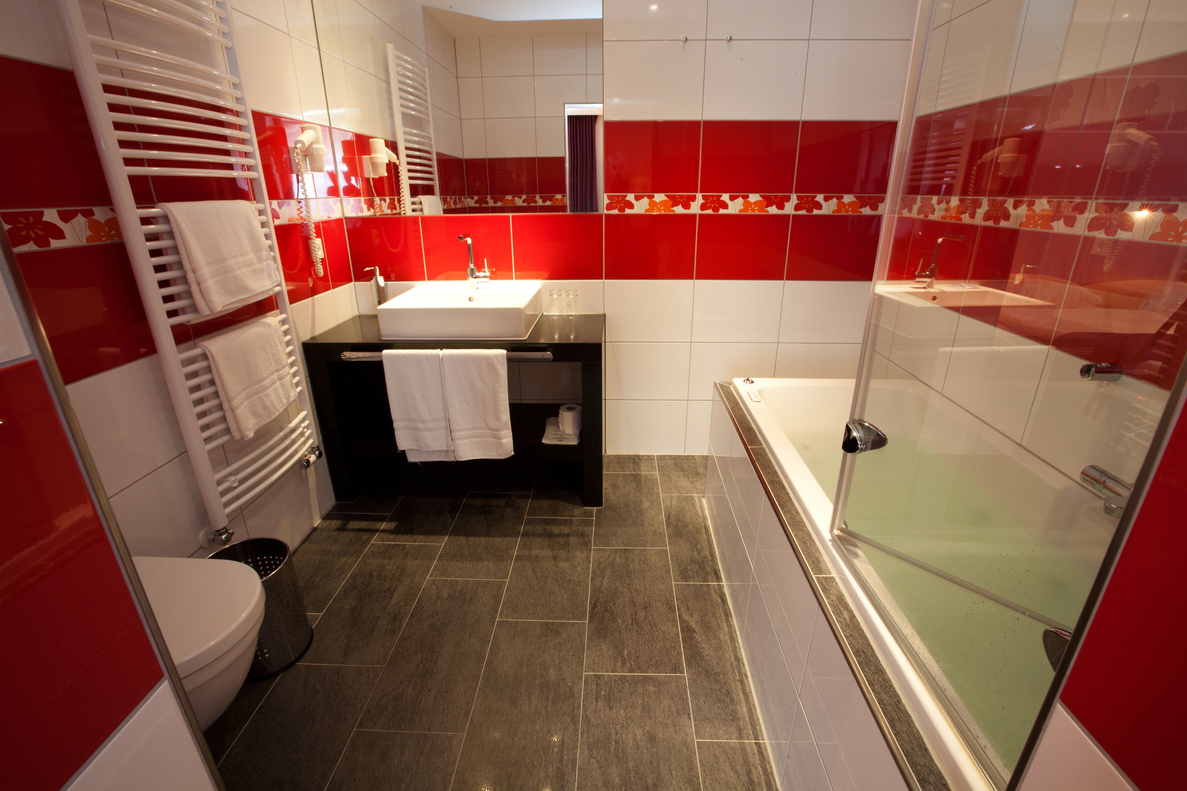 Un baño moderno con cabina de ducha de vidrio, tocador negro con lavamanos y inodoro blanco.