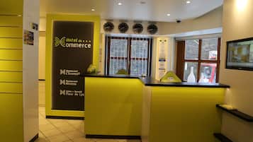 A hotel reception area with a yellow and black color scheme, featuring a counter, a reception desk, and a wall with a clock and city names.