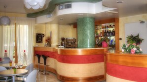 Zona de bar con mostrador curvo, taburetes y una variedad de botellas en estantes.