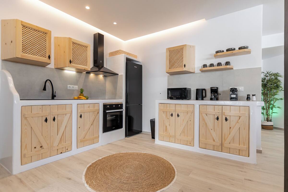 A modern kitchen with wooden cabinets, a black refrigerator, a microwave, and a coffee machine.