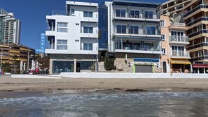 Un hotel frente al mar con varios pisos, balcones y un restaurante visible.