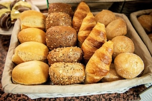 Una cesta con panes y pasteles varios.