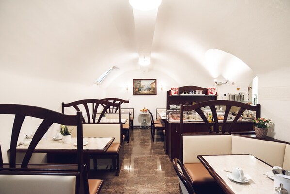 Un restaurante con cabinas y mesas, piso de baldosas y un cuadro en la pared.