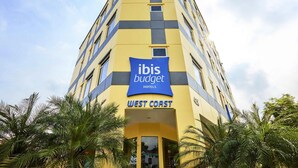 A tall hotel building with a yellow facade and a blue sign for ibis budget hotels. - ibis budget Singapore West Coast (Singapore)