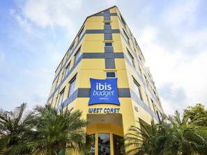 Um edifício alto de hotel com fachada amarela e placa azul para ibis budget hotels.