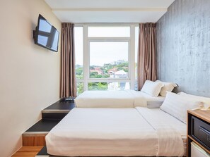 A hotel room with a large bed, a TV mounted on the wall, and a view of the city through the window. - ibis budget Singapore West Coast (Singapore)
