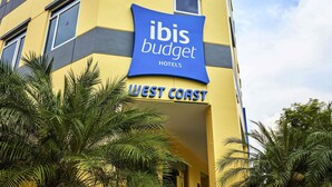 A building with a sign for ibis budget hotels and a label indicating it's the West Coast location. - ibis budget Singapore West Coast (Singapore)