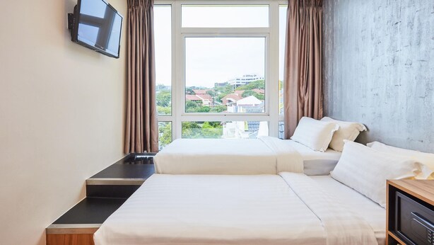 A hotel room with a large bed, a TV mounted on the wall, and a view of the city through the window. - ibis budget Singapore West Coast (Singapore)