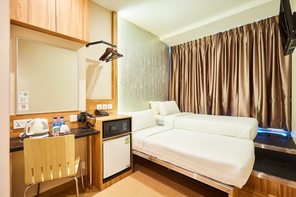 Ein Hotelzimmer mit einem Bett, einem Schreibtisch mit Telefon, einem kleinen Kühlschrank und einem Spiegel.