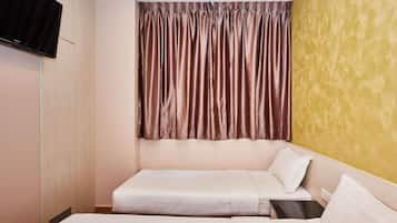 Habitación de hotel con dos camas, un televisor de pantalla plana montado en la pared y una ventana con cortinas marrones.