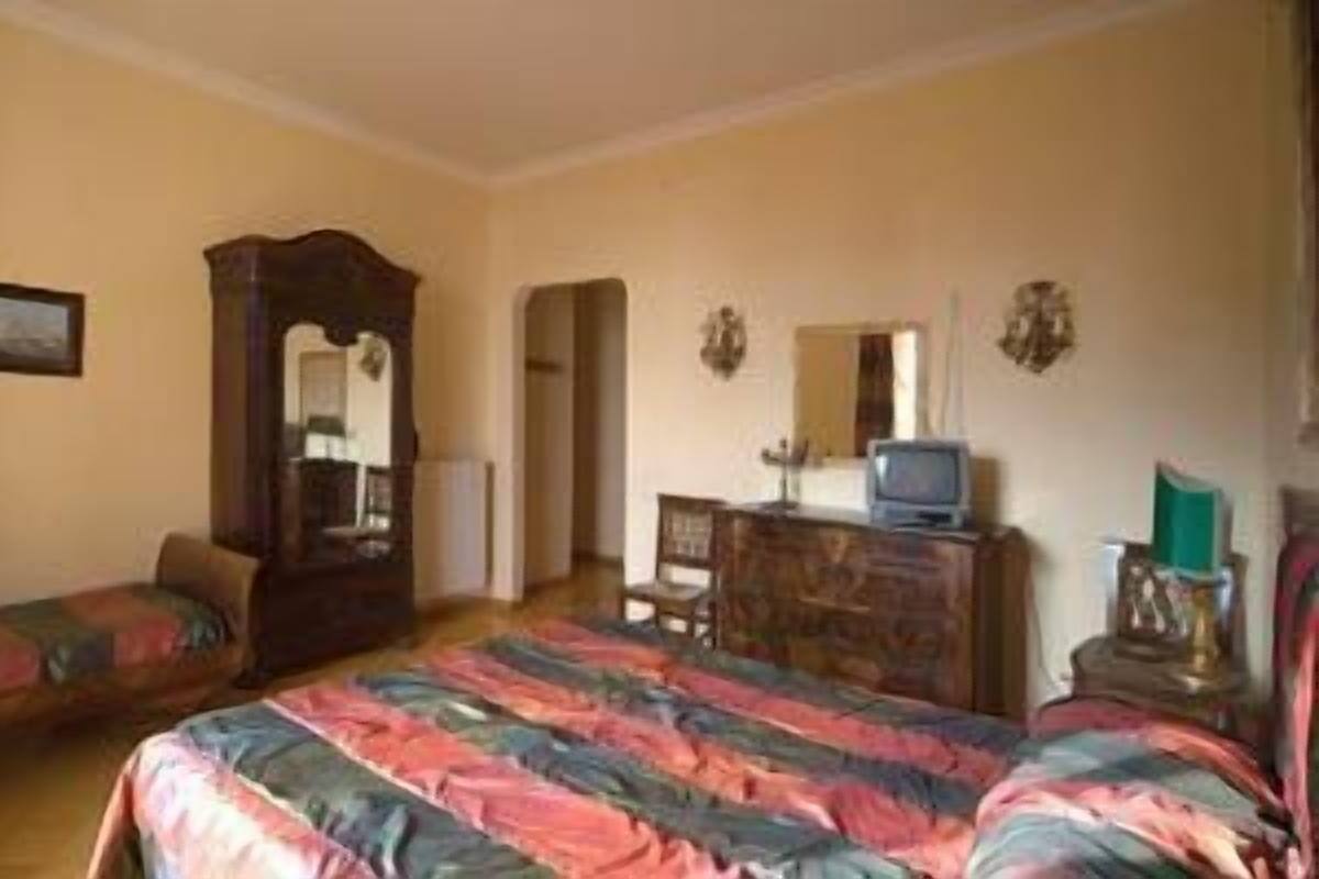 A bedroom with a bed, a dresser, a mirror, and a television.