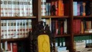 Una biblioteca con estanterías llenas de libros, un escritorio de madera y una silla.