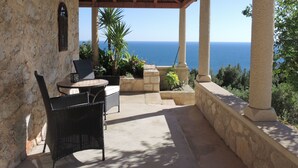 A covered outdoor seating area with stone walls, a pergola, and a view of the sea. - Villa Perka (Hvar)