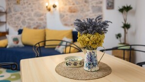 A room with a wooden table, a vase with flowers, a small decorative bowl, and a stone wall in the background. - Villa Perka (Hvar)